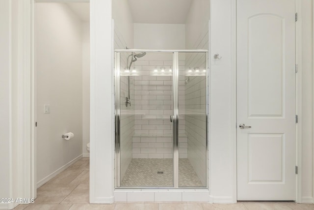 bathroom with tile patterned flooring, a shower with door, and toilet