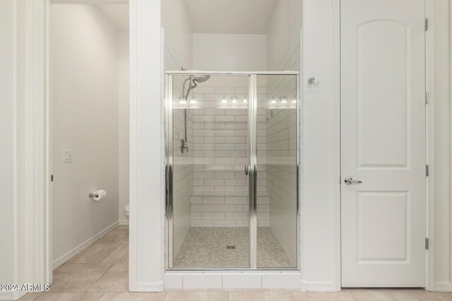 bathroom with an enclosed shower, tile patterned floors, and toilet