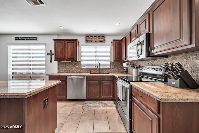 kitchen featuring light tile patterned flooring, stainless steel appliances, a wealth of natural light, and sink