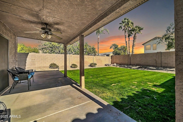 yard at dusk with a patio and ceiling fan