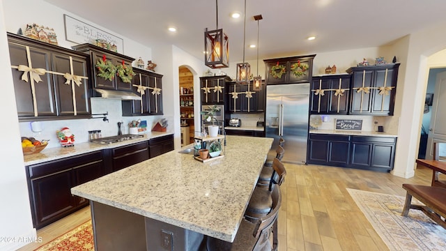 kitchen featuring appliances with stainless steel finishes, pendant lighting, a breakfast bar area, a kitchen island, and light wood-type flooring