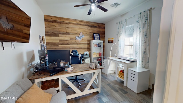 home office featuring ceiling fan, wood walls, and dark hardwood / wood-style flooring