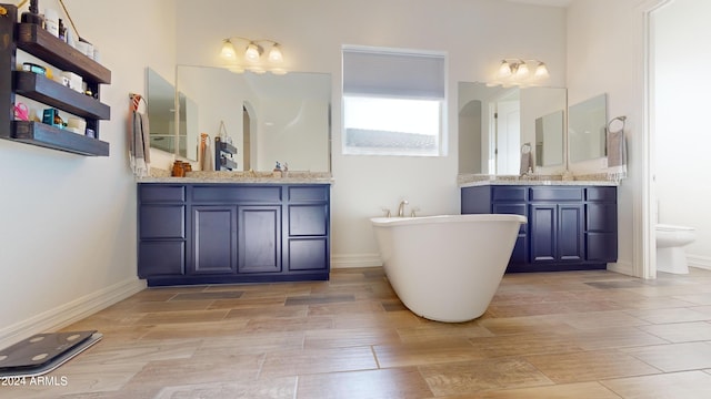 bathroom featuring wood-type flooring, vanity, toilet, and a bathtub