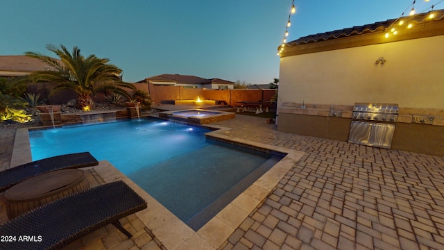 pool at dusk with grilling area, pool water feature, an in ground hot tub, area for grilling, and a patio area