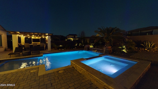 pool at night featuring an in ground hot tub and a patio