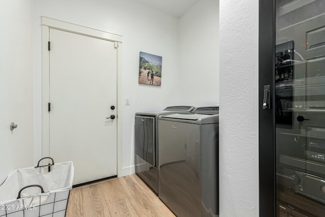 laundry area featuring washer and clothes dryer and light hardwood / wood-style floors