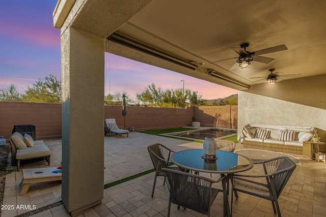 patio terrace at dusk featuring an outdoor living space and ceiling fan