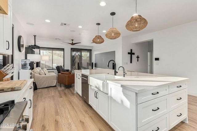 kitchen featuring sink, decorative light fixtures, light hardwood / wood-style flooring, an island with sink, and white cabinets