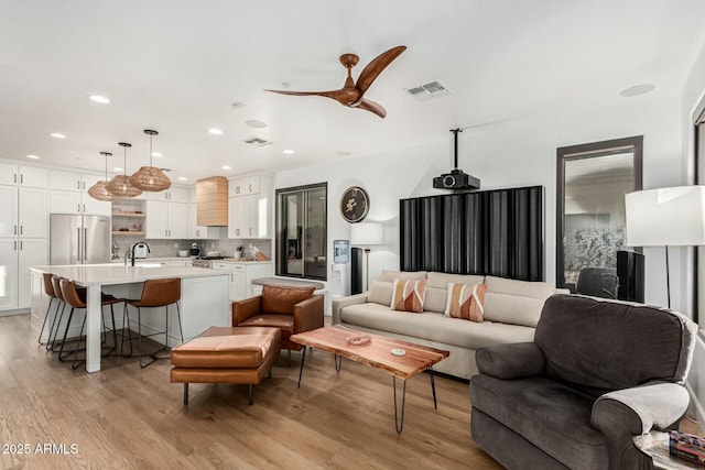 living room featuring ceiling fan, sink, and light hardwood / wood-style floors