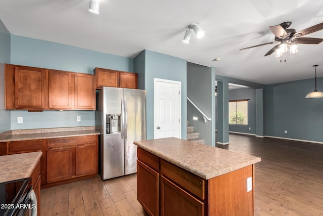kitchen with a ceiling fan, a center island, brown cabinets, stainless steel appliances, and light wood-style flooring