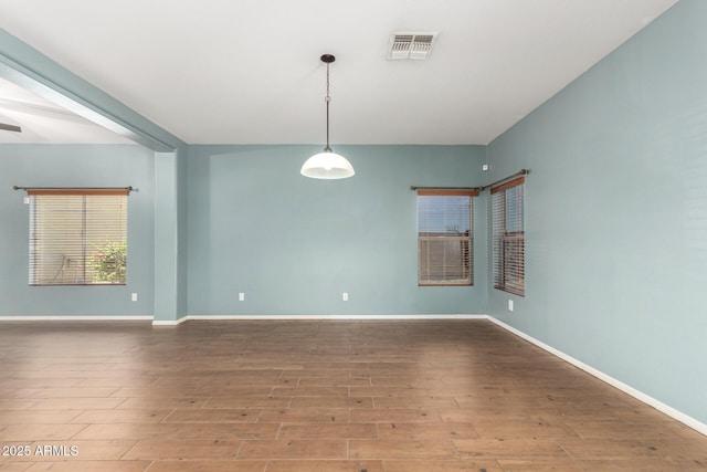 unfurnished room with baseboards, wood finished floors, and visible vents