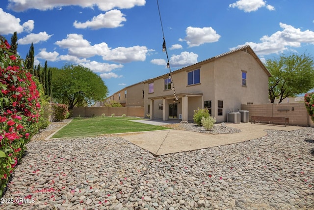 back of house featuring a fenced backyard, a patio, stucco siding, and a lawn