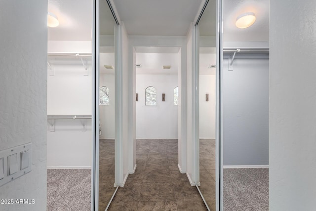 hall with a textured wall and tile patterned floors
