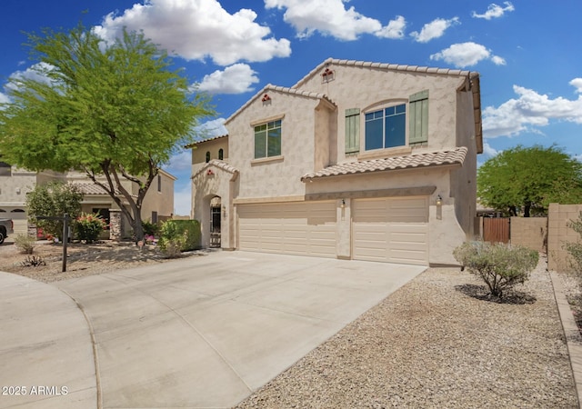 mediterranean / spanish house with fence, a tile roof, a garage, stucco siding, and driveway
