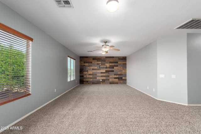 carpeted spare room with visible vents, a ceiling fan, and baseboards