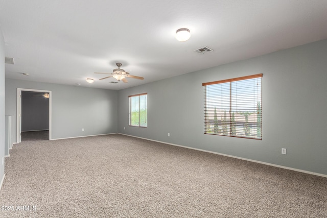 carpeted spare room featuring baseboards, a ceiling fan, and visible vents