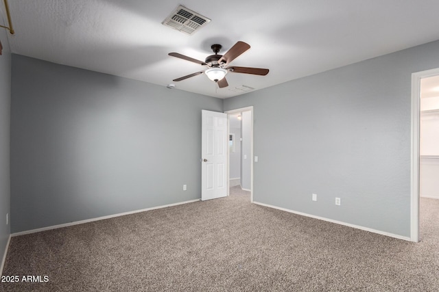 carpeted spare room featuring baseboards, ceiling fan, and visible vents