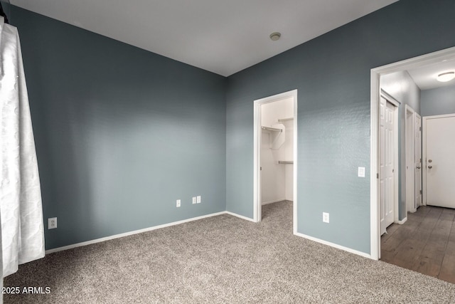 unfurnished bedroom with carpet floors, baseboards, and a spacious closet