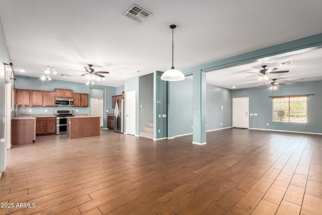 unfurnished living room with a sink, ceiling fan, visible vents, and wood finished floors