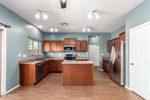 kitchen with a sink, brown cabinetry, a center island, stainless steel appliances, and visible vents