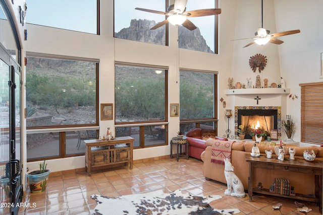 tiled living room with ceiling fan and a towering ceiling