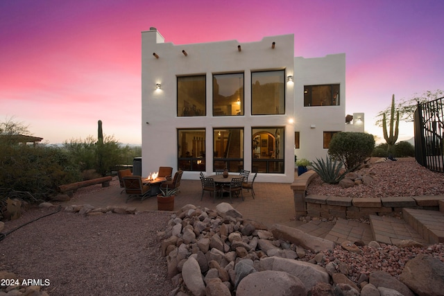 back house at dusk featuring a patio