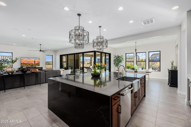 kitchen with hanging light fixtures, sink, an island with sink, and ceiling fan with notable chandelier