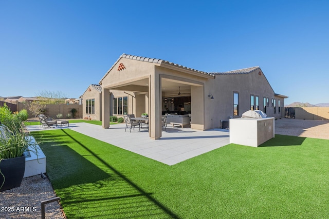 back of house with ceiling fan, a lawn, and a patio