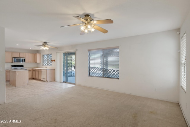 kitchen featuring a kitchen island, light brown cabinetry, dishwasher, light colored carpet, and range