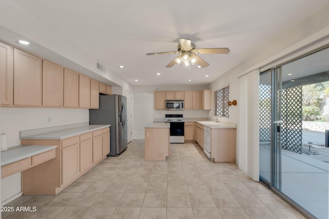 kitchen featuring light brown cabinetry, sink, a kitchen island, ceiling fan, and stainless steel appliances