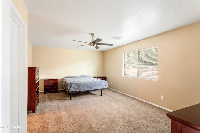 carpeted bedroom with ceiling fan and a textured ceiling