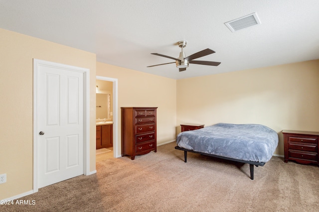 bedroom featuring ceiling fan, light colored carpet, and connected bathroom