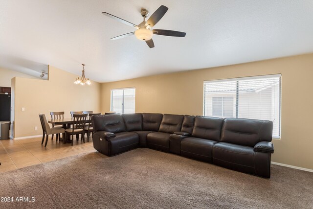 living room with ceiling fan with notable chandelier, vaulted ceiling, and light colored carpet