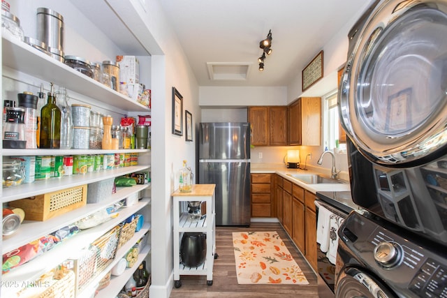 interior space featuring stacked washer / drying machine, sink, track lighting, dark hardwood / wood-style floors, and stainless steel fridge