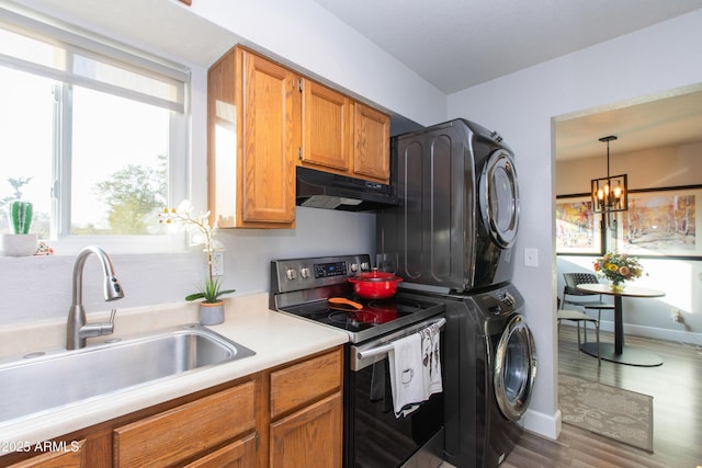 interior space with sink, a notable chandelier, hardwood / wood-style floors, and stacked washing maching and dryer