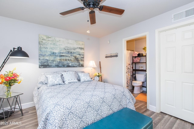 bedroom featuring ceiling fan, ensuite bath, and hardwood / wood-style floors