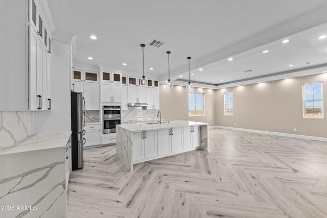 kitchen featuring white cabinetry, sink, hanging light fixtures, and a kitchen island with sink