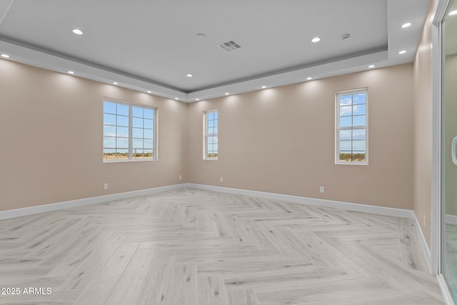 unfurnished room with light parquet flooring and a tray ceiling