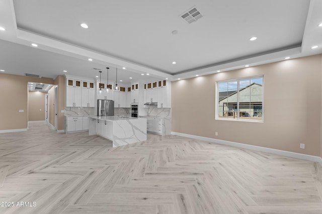 unfurnished living room featuring light parquet floors, a raised ceiling, and sink