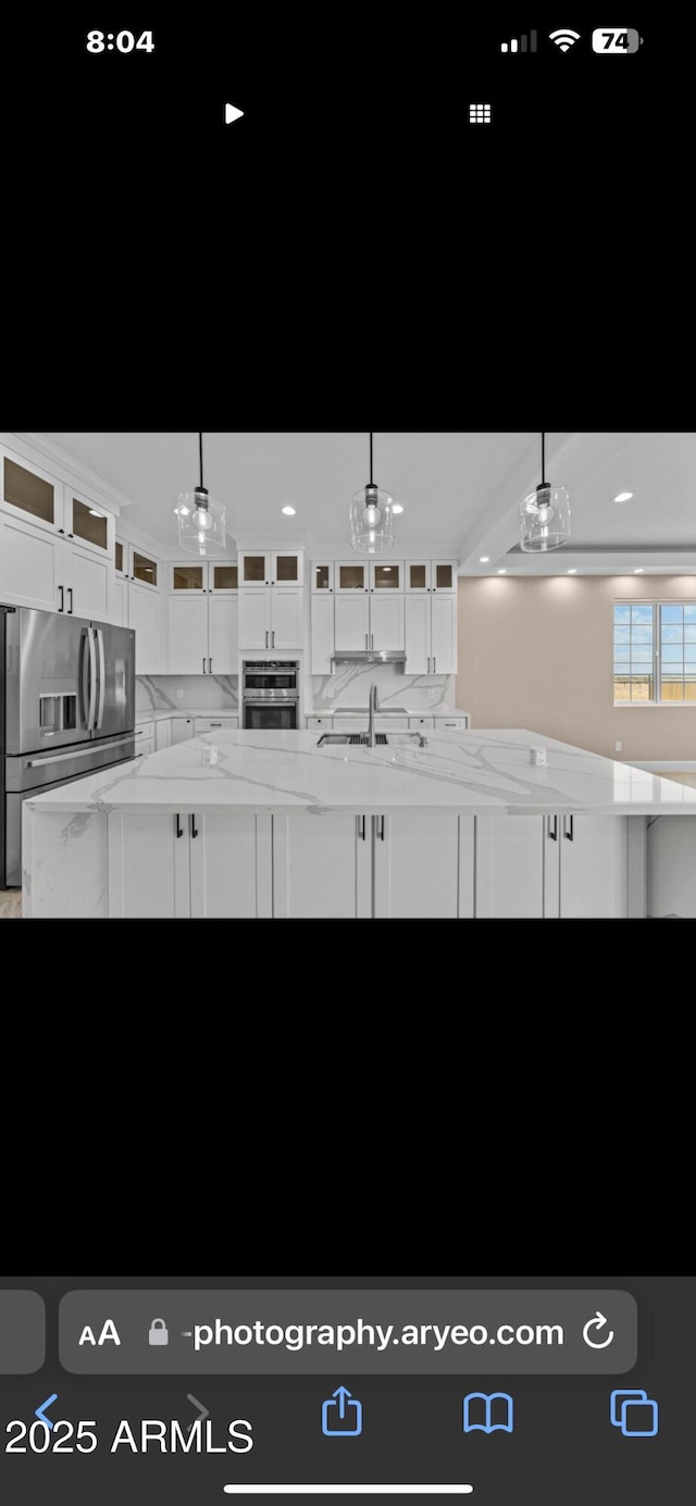 kitchen featuring decorative light fixtures, white cabinets, and appliances with stainless steel finishes