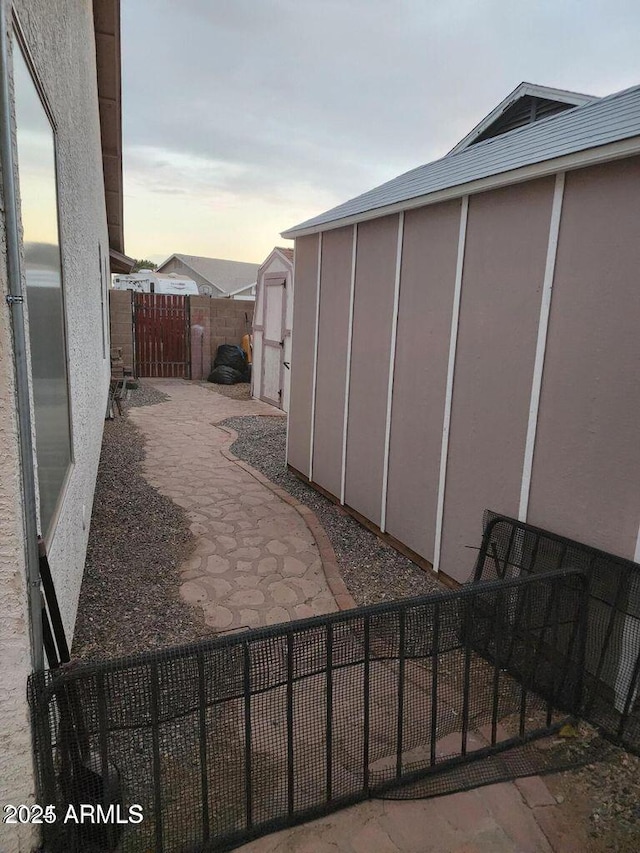 patio terrace at dusk with fence private yard, an outdoor structure, and a shed