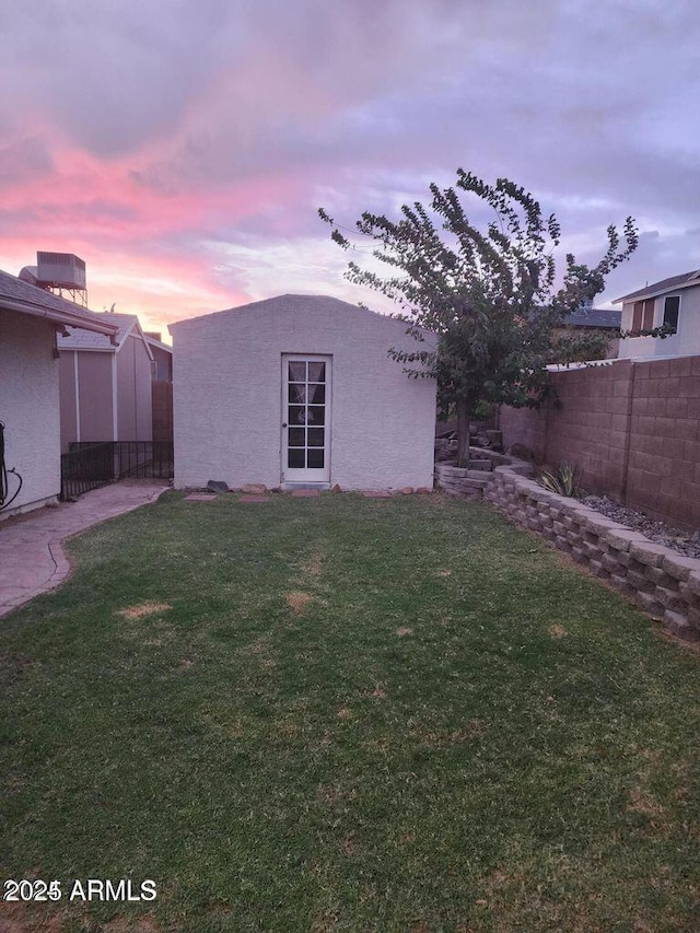 yard at dusk featuring fence and an outdoor structure