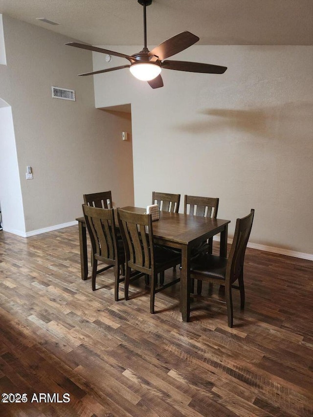 dining room featuring dark wood-style flooring, visible vents, vaulted ceiling, and baseboards