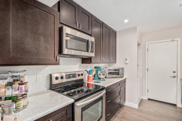 kitchen featuring dark brown cabinets, light hardwood / wood-style floors, and stainless steel appliances