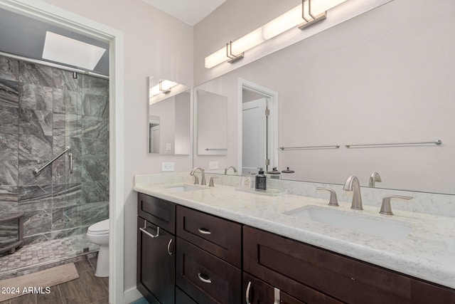 bathroom with a tile shower, vanity, hardwood / wood-style flooring, and toilet