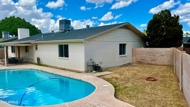 rear view of property with a fenced in pool, a yard, and a patio area