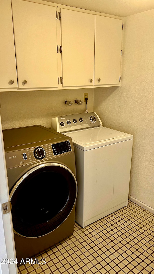 clothes washing area featuring washer and dryer and cabinets