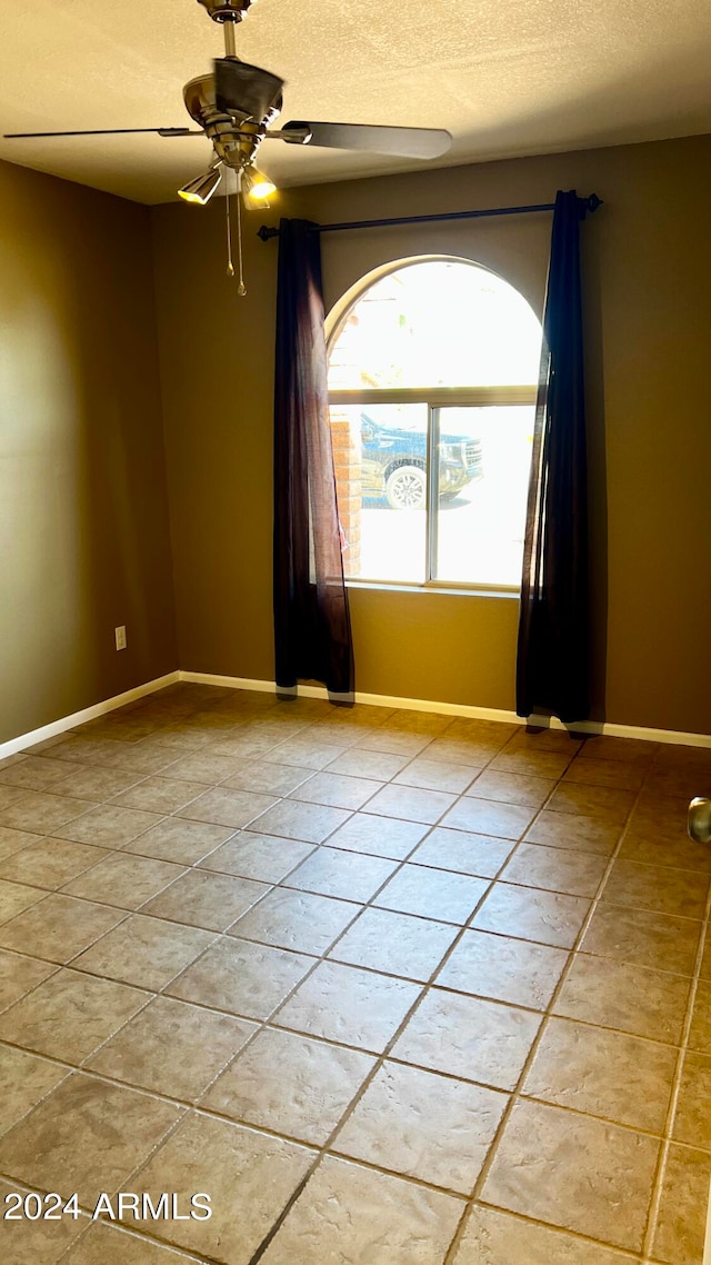 tiled spare room with ceiling fan and a textured ceiling