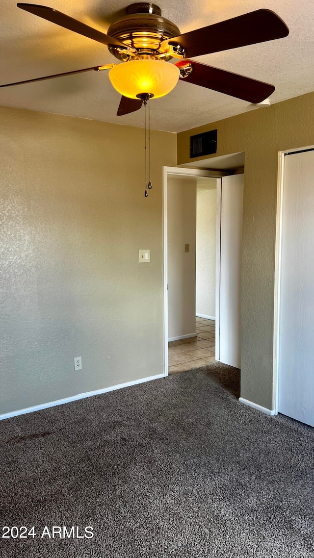 carpeted empty room with ceiling fan and a textured ceiling