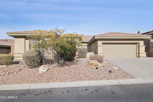 prairie-style home with concrete driveway, an attached garage, a tiled roof, and stucco siding